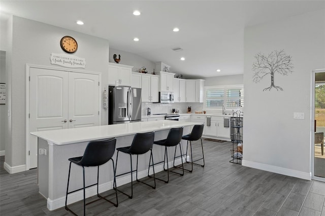 kitchen featuring stainless steel appliances, a kitchen island, white cabinets, and a kitchen breakfast bar