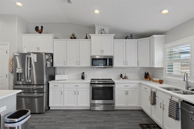 kitchen featuring lofted ceiling, sink, appliances with stainless steel finishes, decorative backsplash, and white cabinets