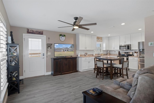 living room featuring ceiling fan, a healthy amount of sunlight, and light hardwood / wood-style flooring