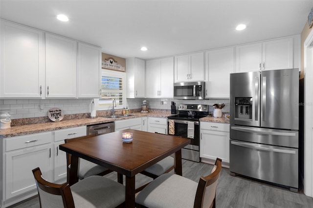 kitchen with white cabinetry, appliances with stainless steel finishes, sink, and light stone counters