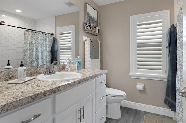 bathroom with walk in shower, vanity, toilet, and wood-type flooring