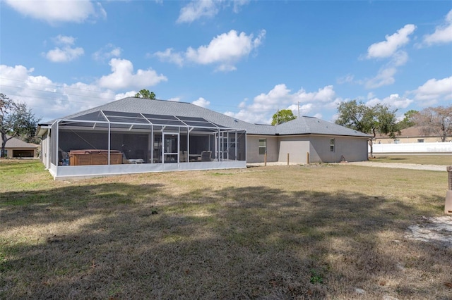 back of property with a yard, a lanai, and a hot tub