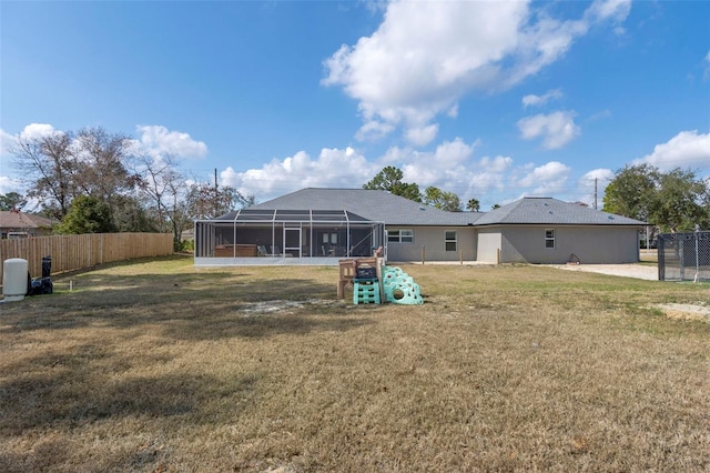 rear view of house with a yard and glass enclosure