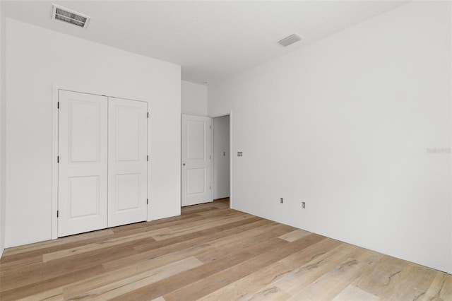 unfurnished bedroom with light wood-type flooring and a closet