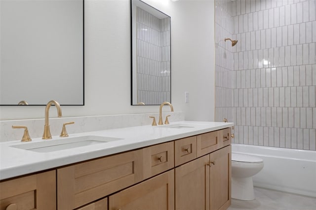 full bathroom featuring tiled shower / bath, vanity, and toilet