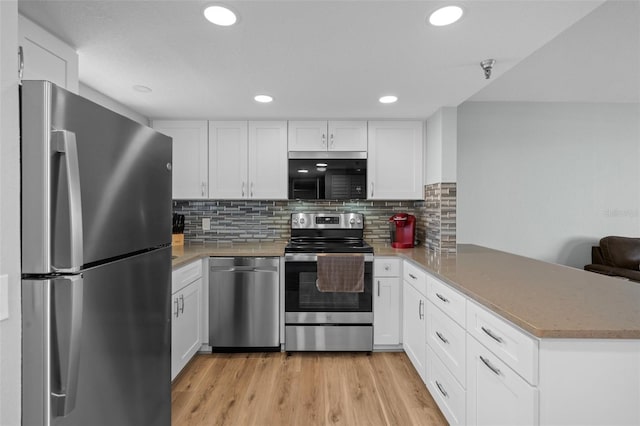 kitchen with white cabinets, decorative backsplash, kitchen peninsula, stainless steel appliances, and light wood-type flooring