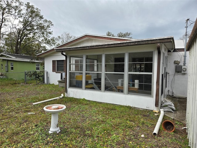 rear view of property featuring a sunroom and a yard