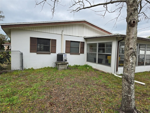 back of property featuring central AC and a lawn