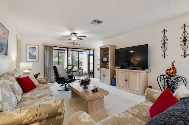 living room with ceiling fan, light carpet, and a textured ceiling