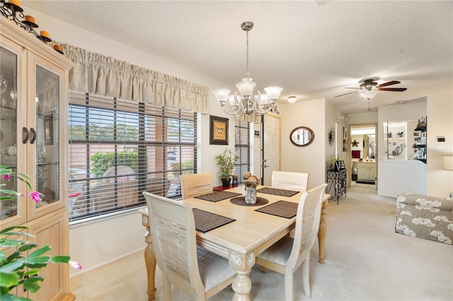 dining area with light carpet, ceiling fan with notable chandelier, and a textured ceiling