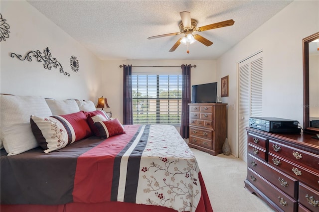 bedroom with ceiling fan, light carpet, a textured ceiling, and a closet