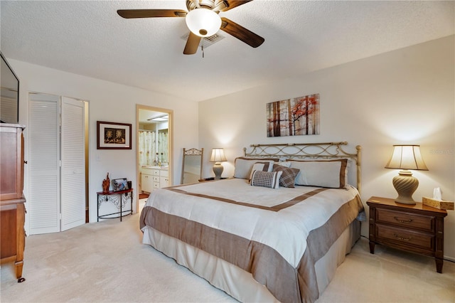 bedroom featuring ensuite bath, light carpet, a textured ceiling, a closet, and ceiling fan