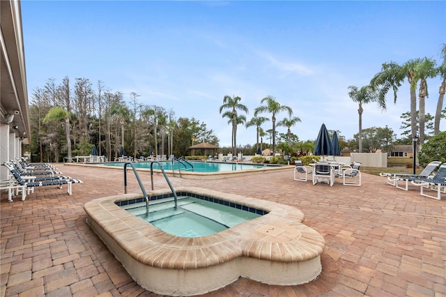 view of swimming pool with a hot tub and a patio area