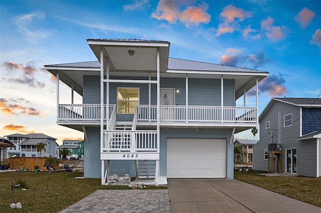 raised beach house with a garage, a yard, and covered porch