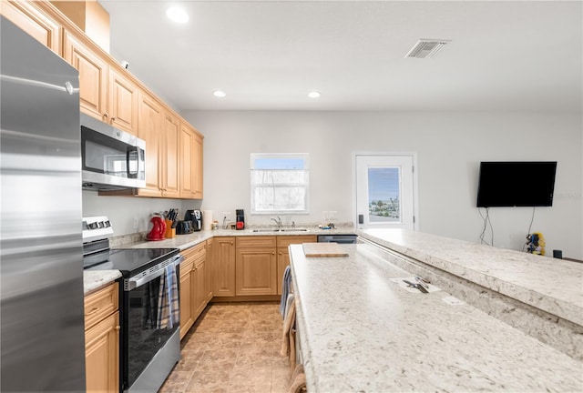 kitchen featuring appliances with stainless steel finishes, light brown cabinetry, and sink