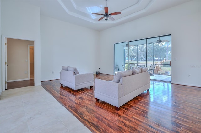 living room with a towering ceiling, a raised ceiling, and hardwood / wood-style floors