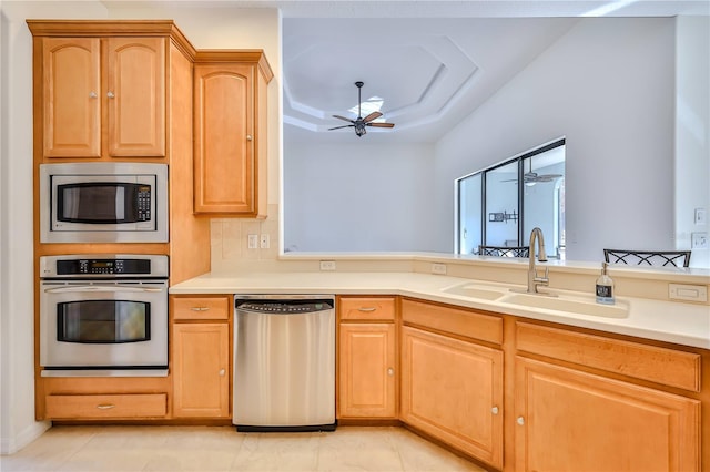 kitchen featuring sink, light tile patterned floors, ceiling fan, appliances with stainless steel finishes, and a raised ceiling