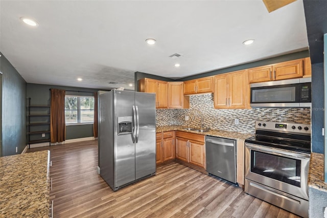 kitchen with stainless steel appliances, light stone counters, light wood-style flooring, and visible vents