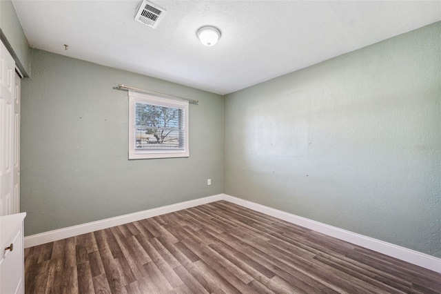 unfurnished bedroom featuring dark wood-style floors, a closet, visible vents, and baseboards