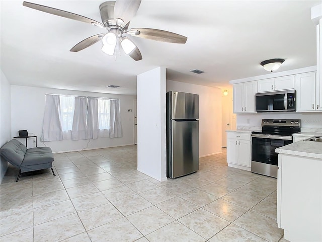 kitchen with light tile patterned floors, stainless steel appliances, white cabinets, and ceiling fan