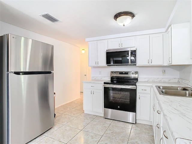 kitchen featuring sink, light tile patterned floors, white cabinetry, stainless steel appliances, and light stone countertops