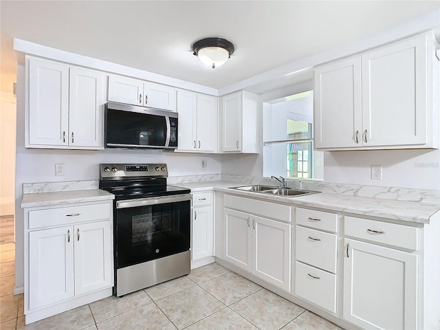 kitchen featuring light tile patterned flooring, white cabinetry, sink, stainless steel appliances, and light stone countertops