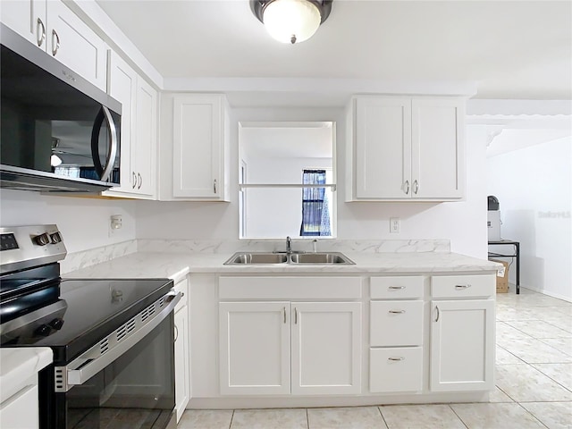 kitchen featuring sink, light stone counters, light tile patterned floors, stainless steel appliances, and white cabinets