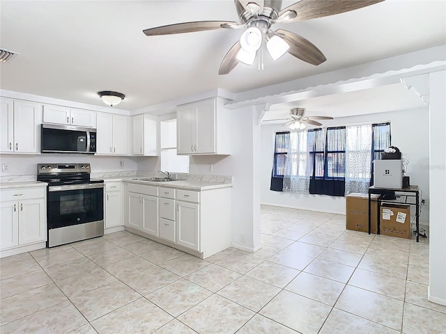 kitchen featuring stainless steel appliances, sink, light tile patterned floors, and white cabinets