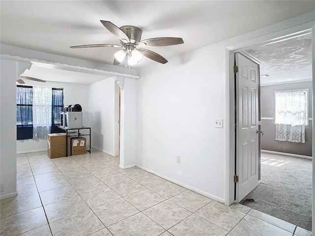 spare room featuring a wealth of natural light, ceiling fan, and light tile patterned flooring