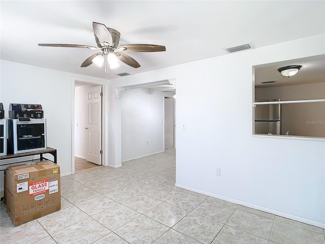 tiled empty room featuring ceiling fan