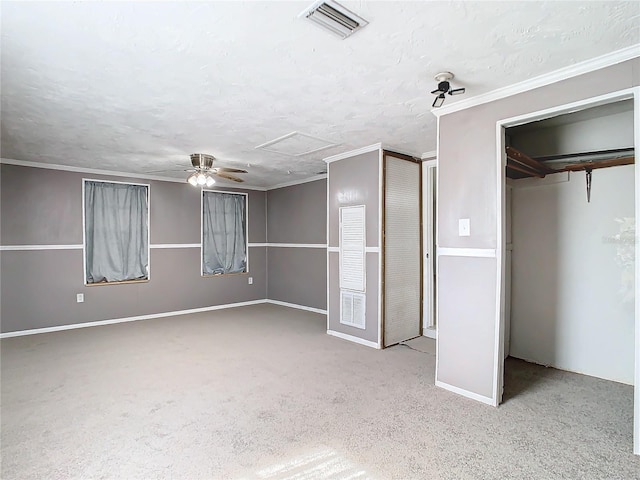 unfurnished bedroom with crown molding, two closets, light colored carpet, and a textured ceiling