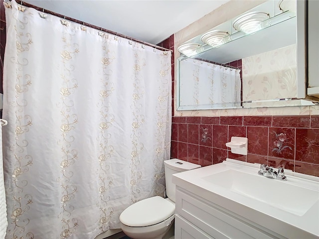 bathroom with vanity, toilet, and tile walls