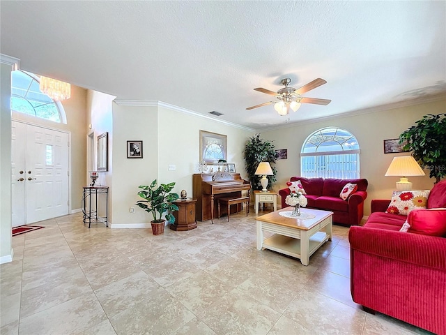 living room featuring baseboards, visible vents, a ceiling fan, a textured ceiling, and crown molding