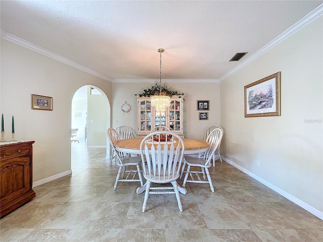 dining room with arched walkways, visible vents, crown molding, and baseboards