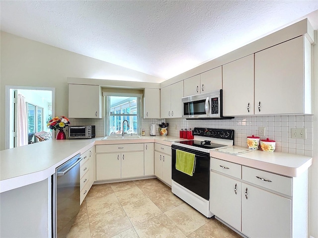 kitchen with lofted ceiling, light countertops, appliances with stainless steel finishes, and a sink