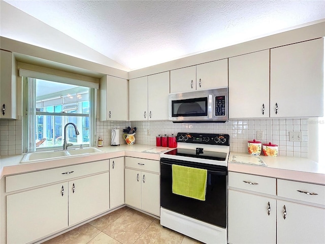 kitchen featuring a textured ceiling, a sink, light countertops, electric range oven, and stainless steel microwave