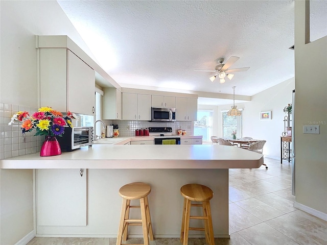 kitchen with electric stove, stainless steel microwave, a sink, and light countertops