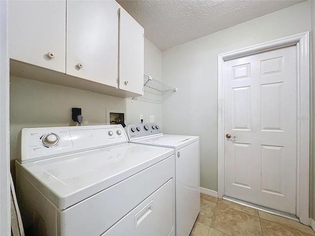 laundry area featuring cabinet space, washer and clothes dryer, a textured ceiling, and light tile patterned flooring