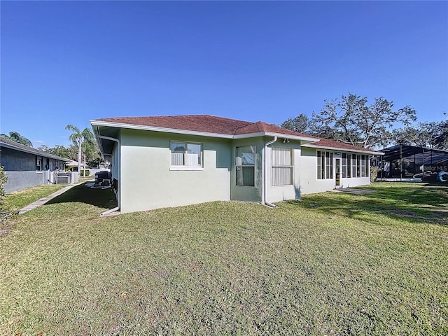 view of side of home with stucco siding and a yard