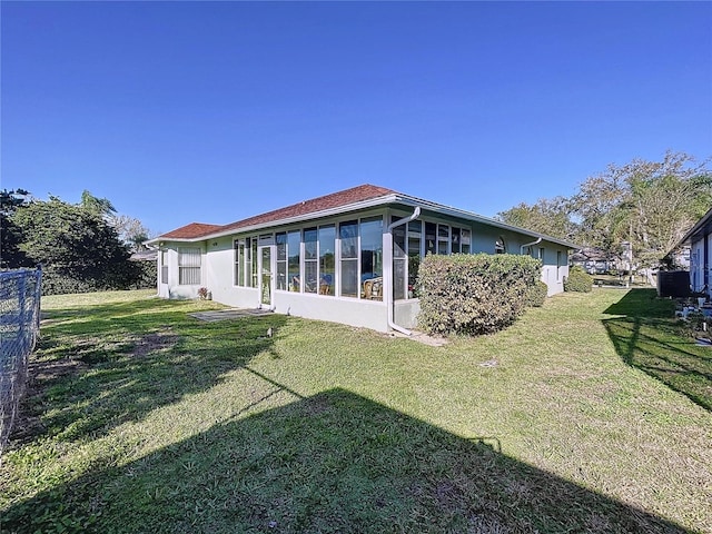 rear view of house with a yard and a sunroom