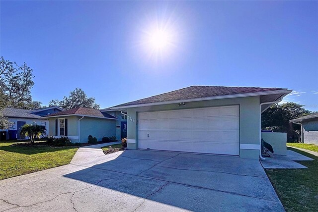 ranch-style house featuring driveway, an attached garage, a front lawn, and stucco siding