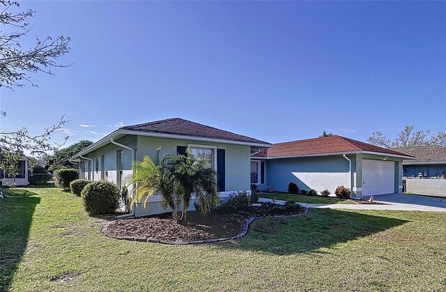 view of front of property with an attached garage, driveway, a front lawn, and stucco siding