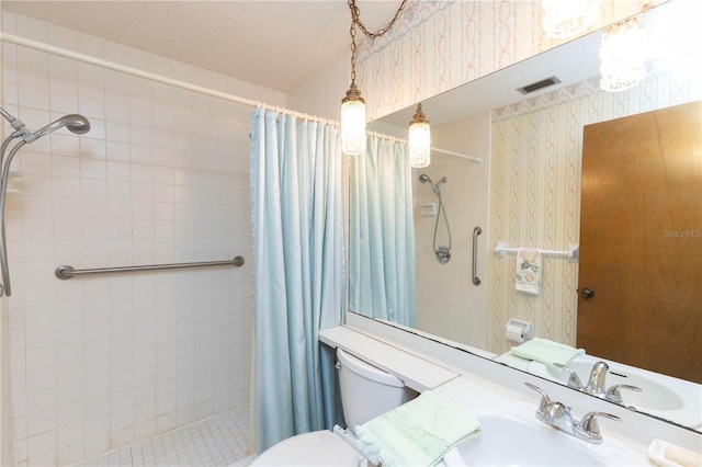 bathroom featuring toilet, curtained shower, sink, and a textured ceiling