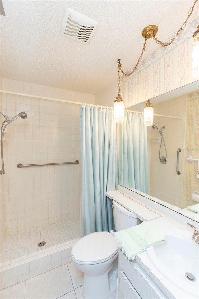 bathroom featuring tile patterned flooring, vanity, a textured ceiling, toilet, and walk in shower