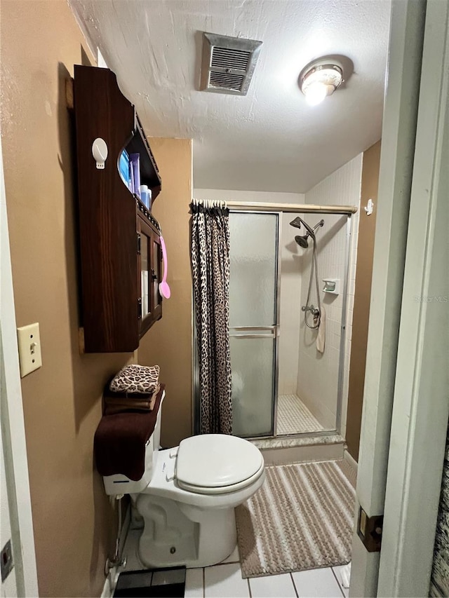 bathroom featuring toilet, tile patterned flooring, a shower with door, and a textured ceiling