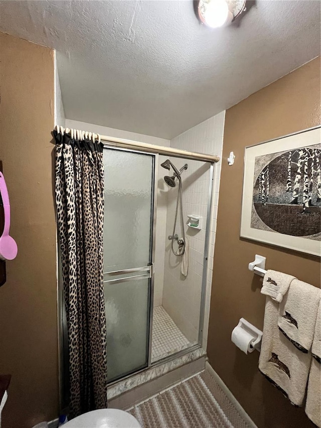 bathroom featuring an enclosed shower, a textured ceiling, and toilet