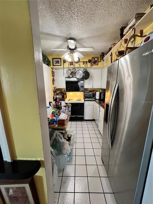 kitchen featuring a textured ceiling, light tile patterned floors, stainless steel fridge, ceiling fan, and white cabinets