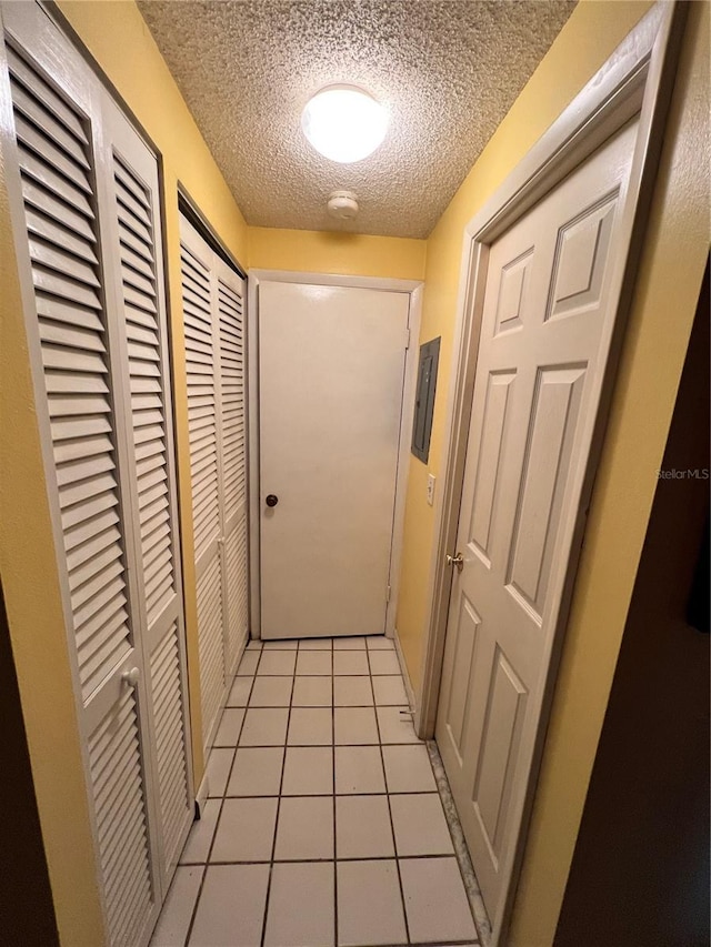 hallway featuring light tile patterned flooring and a textured ceiling