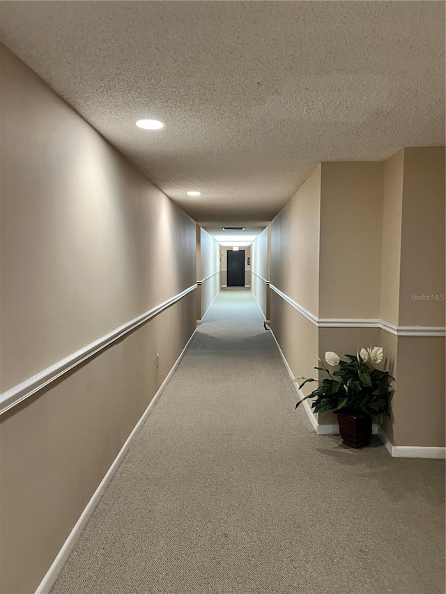 hallway with carpet floors and a textured ceiling