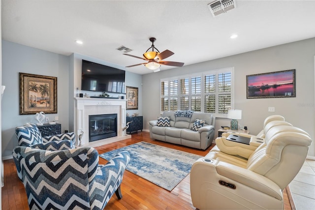18819 Sunterra Dr, Land O Lakes, FL 34638 - living room with a ceiling fan, light wood-style floors, a tiled fireplace, recessed lighting, and baseboards